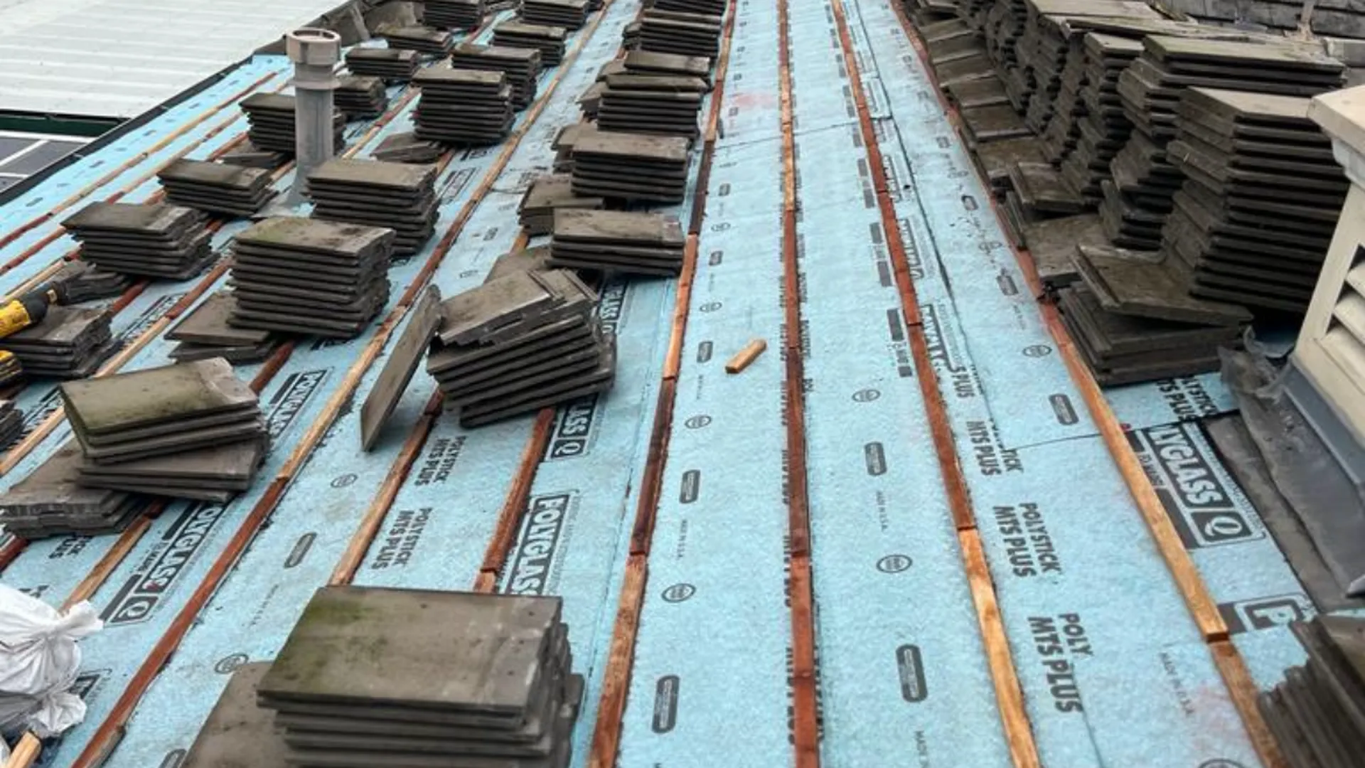 Tile roof re-lay with new underlayment and battens, tiles staged on the roof